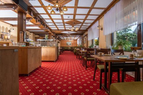 Hotel Garni Zur Alten Post في ليمبروتش: مطعم بطاولات وكراسي وسجادة حمراء