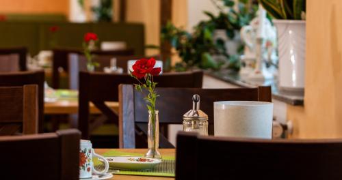 a red rose in a vase on a table at Hotel Garni Zur Alten Post in Lembruch