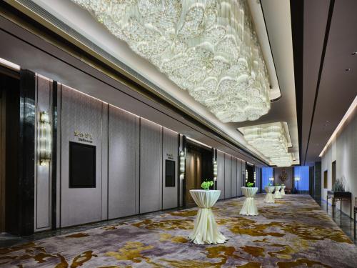a hallway with tables and a large chandelier at Wanda Vista Changchun in Changchun