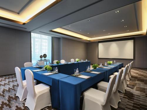 a conference room with a long blue table and white chairs at Wanda Vista Changchun in Changchun