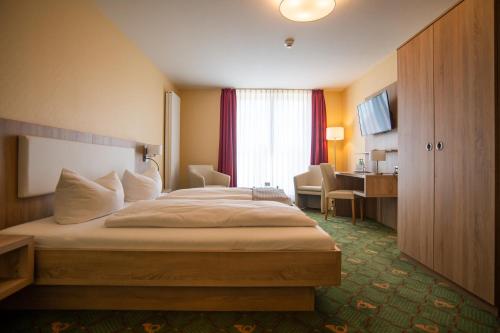 a hotel room with a bed and a desk at Hotel Garni Zur Alten Post in Lembruch