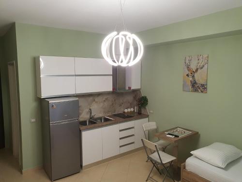 La cuisine est équipée d'un évier, d'un réfrigérateur et d'une table. dans l'établissement Darla Sea View Apartment, à Vlorë