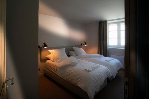 1 dormitorio con 1 cama con sábanas blancas y ventana en The View - Gite Mont Dore, en Montpeyroux