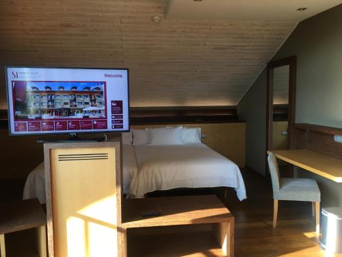 a bedroom with a bed, desk and television at SOMMOS Hotel Aneto in Benasque