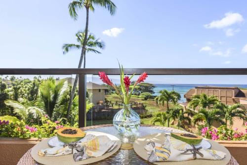 a table with two plates of food and a view of the ocean at Kahana Villa F406 in Lahaina