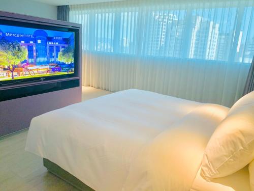 a bedroom with a bed and a flat screen tv at Mercure Fuzhou Downtown in Fuzhou