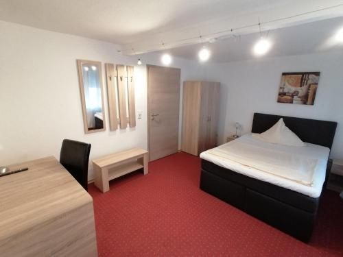 1 dormitorio con cama, escritorio y mesa en Landhotel Adler, en Selters