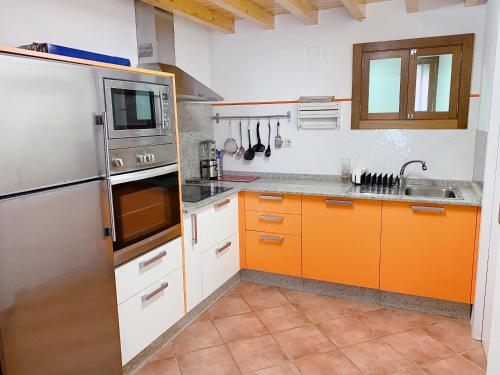 La cuisine est équipée de placards orange et d'un réfrigérateur en acier inoxydable. dans l'établissement A Casa de Feli, à Muros