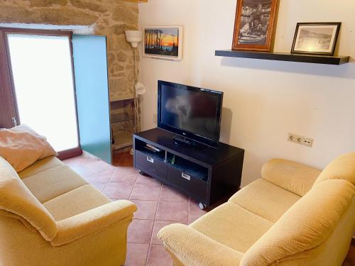 a living room with two couches and a flat screen tv at A Casa de Feli in Muros