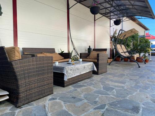 eine Terrasse mit Korbmöbeln auf einem Steinboden in der Unterkunft Casa Corina in Călimăneşti