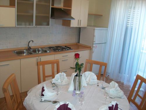 una mesa de comedor con un mantel blanco y una flor. en Apartments Luna, en Tisno