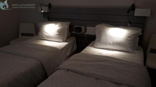 two beds with white pillows in a room at Calme et Central à Jonzac in Jonzac