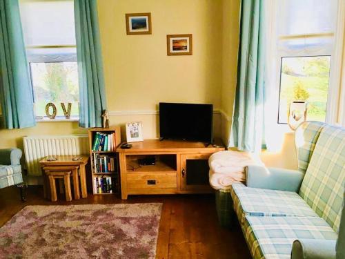 a living room with a couch and a television at Birch Tree Cottage in Westport