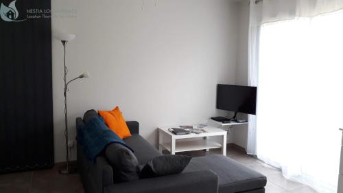 a living room with a couch and a tv at Calme et Central à Jonzac in Jonzac