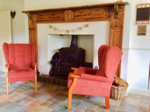 a living room with two chairs and a fireplace at Birch Tree Cottage in Westport