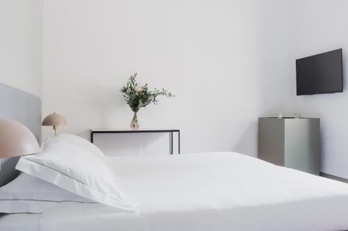a white bedroom with a white bed and a vase of flowers at The Artists' Palace Florence in Florence