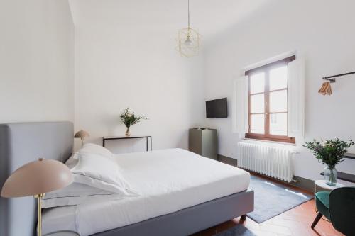 a white bedroom with a bed and a window at The Artists' Palace Florence in Florence