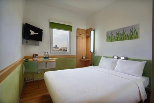 1 dormitorio con 1 cama blanca grande y escritorio en Hotel Caspia Pro Greater Noida, en Greater Noida