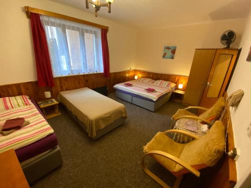 a room with two beds and a chair in it at Penzion Chaloupka in Prague