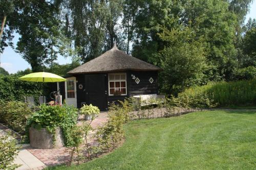 a small black house with a umbrella in a yard at Erve Dikkeboer in Bathmen