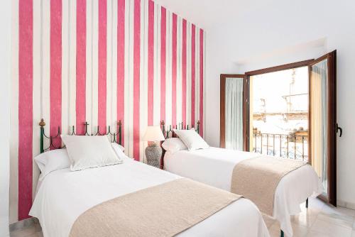 twee bedden in een kamer met rode en witte strepen bij Genteel Home Amor de Dios in Sevilla