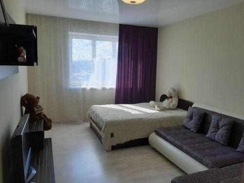 a bedroom with a bed and a couch and a tv at Apartment on Aviatorov 23 in Krasnoyarsk