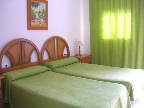 a bedroom with two beds with green sheets and a window at Hotel Antonio Conil in Conil de la Frontera