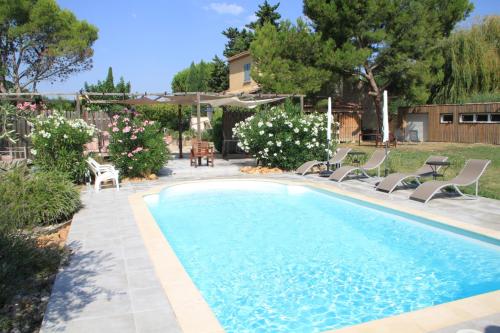 a swimming pool in a yard with chairs and flowers at Le mazet de l'Amathye in Aramon