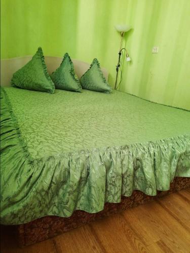 een bed met groene lakens en kussens in een kamer bij Квартира рядом с парком Б. Хмельницкого (центр) из первых рук in Chernihiv