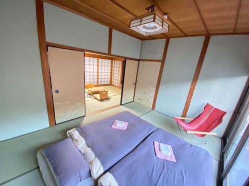 1 dormitorio con 1 cama y 1 silla roja en あまね庵 Villa Amane, en Sakurai