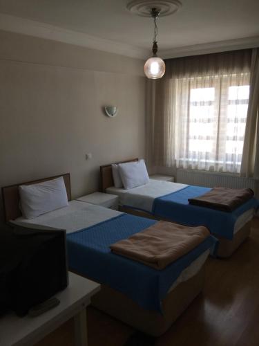 a bedroom with two beds and a tv and a window at Aziziye Hotel in Konya