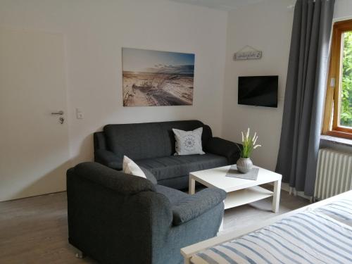 een woonkamer met een bank en een stoel bij Steinmarner Bude 2 in Cuxhaven