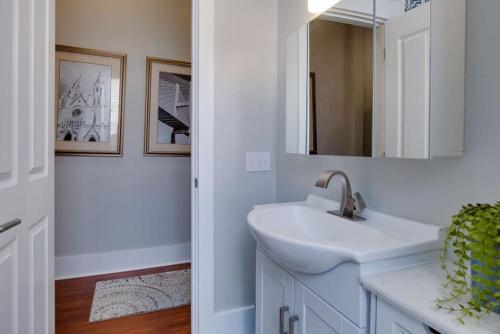 a white bathroom with a sink and a mirror at 111 Waldburg street Beautifully Renovated Historic 5 bedroom 5 bath in Savannah