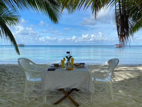 a table with chairs on the beach with the ocean at Mandhoo Inn in Mandhoo