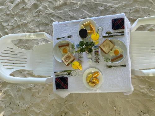 uma mesa de piquenique com comida e utensílios na praia em Mandhoo Inn em Mandhoo