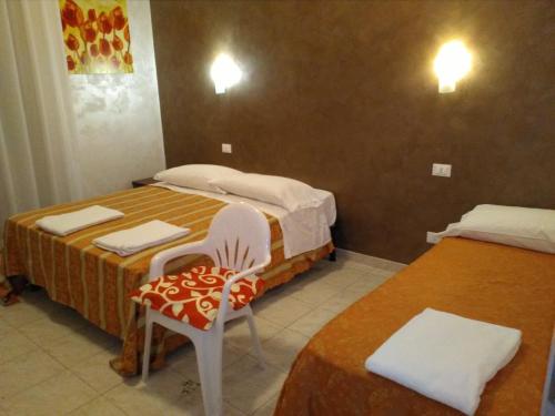 ローマにあるGloria Apartmentのベッド2台と椅子が備わる小さな客室です。