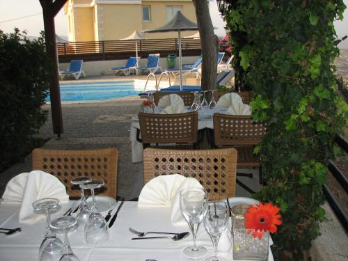 a table with wine glasses and napkins and a pool at Hill View Hotel Apartments in Pissouri
