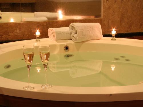 two glasses of champagne in a bath tub with candles at Motel Sunny (Adult Only) in Belo Horizonte