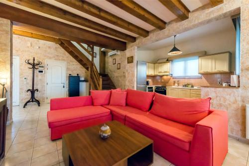 ein Wohnzimmer mit einem roten Sofa und einem Tisch in der Unterkunft Villa Maxim with Private Pool & Tennis Court in Halikounas