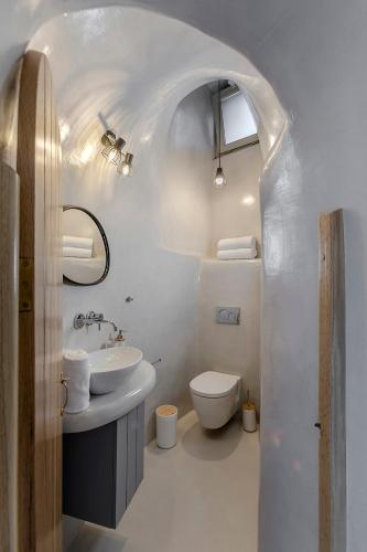a white bathroom with a sink and a toilet at Antron Cave House in Akrotiri