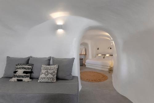 a white room with a couch and a bed at Antron Cave House in Akrotiri