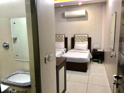 Habitación de hotel con 2 camas y lavamanos en Leela Residency, en Karnal