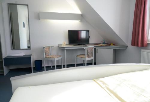 a room with a bed and a desk with a television at Landgasthof Fleischhauer in Büßfeld