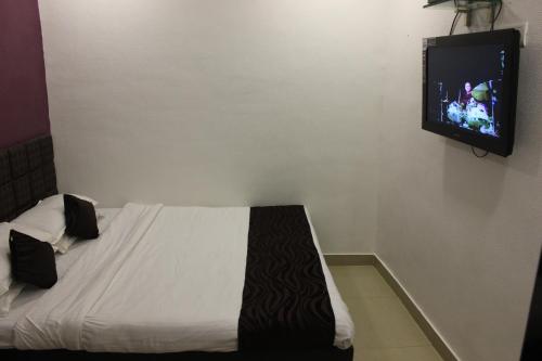 a bedroom with a bed with a tv on the wall at Hotel Fortune in Mumbai