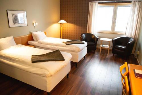 a hotel room with two beds and a table and chairs at Stiftsgården Vårdnäs Hotell in Brokind