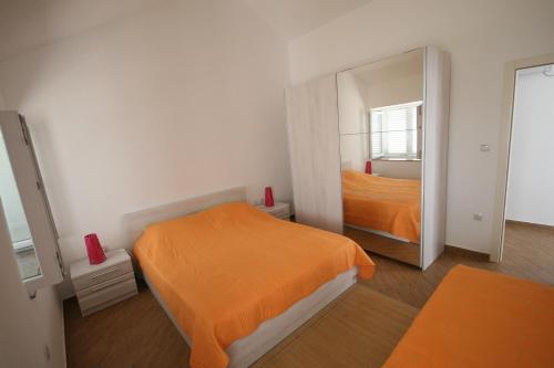 a bedroom with an orange bed and a mirror at House Sakarun in Veli Rat