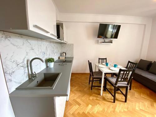 a kitchen with a sink and a table with chairs at Center Warsaw - Apartmenty Jana Pawła II in Warsaw