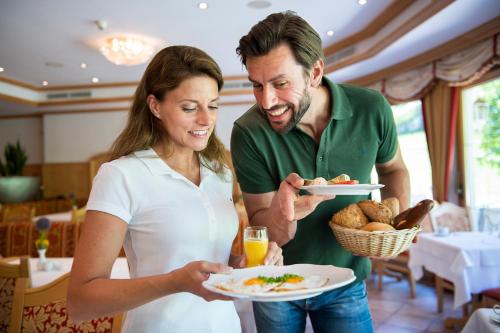 a man and a woman holding a plate of food at Vital Sporthotel Kristall in Finkenberg