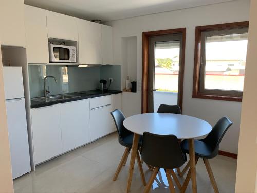 a kitchen with a table and chairs and a table and a refrigerator at Enjoy Esmoriz in Esmoriz