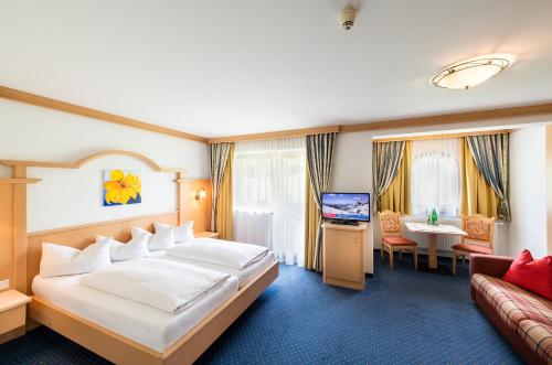 a hotel room with a large bed and a couch at Vital Sporthotel Kristall in Finkenberg